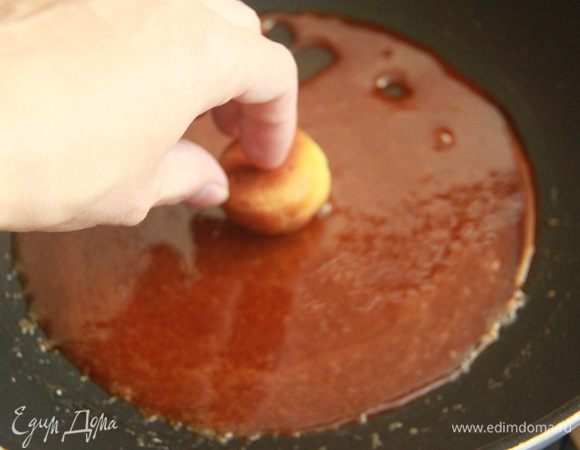 Теперь надо делать все очень быстро: обмакнуть каждый из отложенных профитролей в горячую карамель верхушкой.