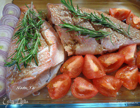 Выложить на каждую рыбку по 2 веточки розмарина. Помидоры разрезать на четвертинки, красный лук — кольцами. Выложить в форму, посолить.