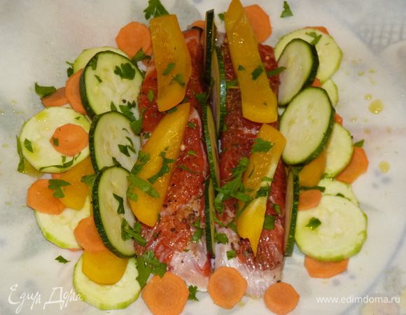 На пергамент выкладываем рыбу с овощами, сбрызгиваем оливковым маслом. Посыпаем зеленью.