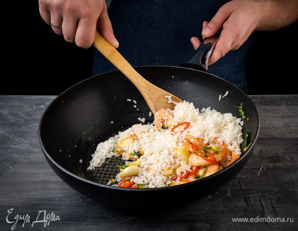 Добавить готовый рис, перемешать и немного обжарить, затем влить соевый соус, еще раз все перемешать и обжарить до готовности.
