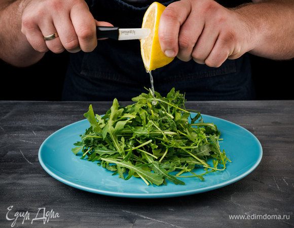 Выложите на тарелку, заранее вымытую и высушенную руколу. Немного сбрызните лимоном.