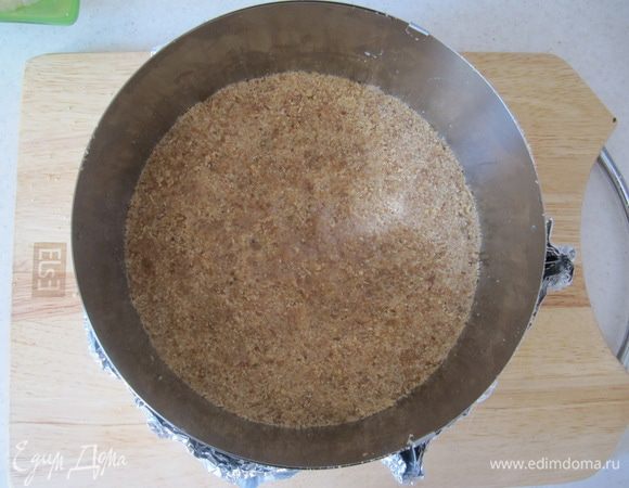 Любое песочное печенье измельчить в блендере в крошку. Смешать с растопленным сливочным маслом в однородную массу. Плотно утрамбовать песочную основу в разъемную форму (у меня разъемное кольцо диаметром 20 см). Поставить форму в холодильник, пока занимаемся следующим слоем, или минимум на 20-30 мин.