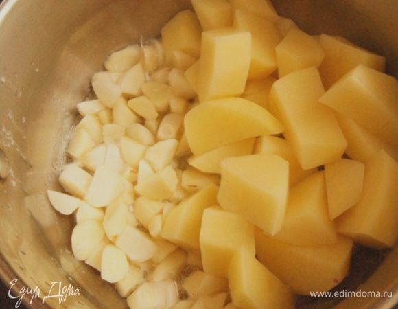 Почистить чеснок и картофель. Чеснок нарезать на 4 части, картофель — крупными кубиками. В кастрюльке разогреть оба вида масла, добавить чеснок и картофель. Тушить около 5 минут, помешивая.
