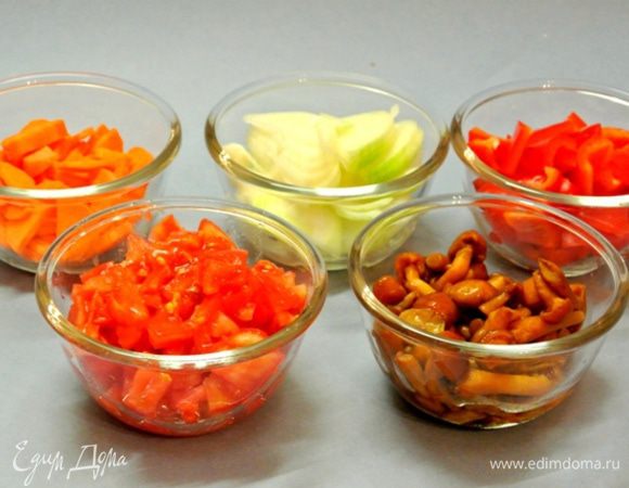 Морковь очистить, нарезать полукружками, перец — крупными кусочками, лук — полукружками. Помидоры надрезать крестообразно, ошпарить кипятком, облить холодной водой, снять кожицу и нарезать кубиками. Выложить грибы, у меня замороженные опята. Если брать свежие грибы, то нарезать ломтиками.