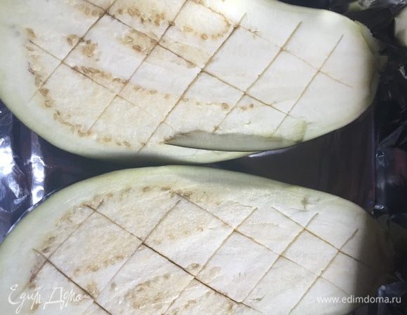 Ставим разогреваться духовку до 200°С. Разрезаем баклажаны на две части, делаем на них крестообразные надрезы и укладываем в форму для запекания. Я выложила форму фольгой.