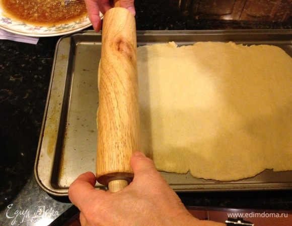 Перенести тесто на противень путем раскручивания, как показано на фото. 