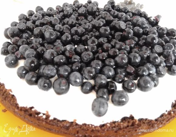 Нижний корж смазать частью крема, приблизительно 3 стол. ложки с большой горкой. Всыпать чернику в количестве 1 — 1,5 стакана, в зависимости от диаметра бисквита.
