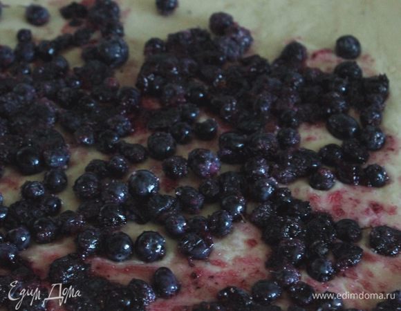 Противень для выпечки застелить бумагой и положить на нее 20 г сливочного масла, порезанного на кусочки. Сверху присыпать 40 г коричневого сахара.
Готовое тесто разделить на три части, каждую раскатать в пласт, выложить ягодную начинку, свернуть рулетом, а затем разрезать на порционные булочки.
