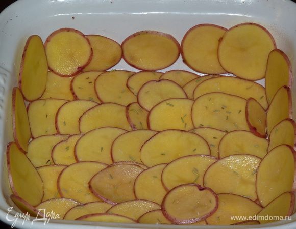 Жаропрочную форму смазать сливочным маслом, оставляя кусочки на дне. Картофель нарезать тонкими слайсами, половину выложить на дно формы, посолить, посыпать розмарином.