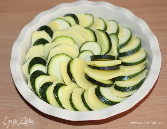 Форму для запекания диаметром 25 см смазать сливочным маслом, выложить туда овощи внахлест в один ряд.