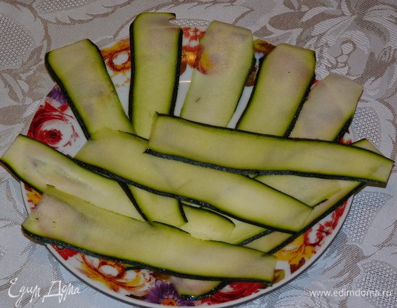 Цукини нарезать вдоль с помощью овощерезки тонкими слайсами.