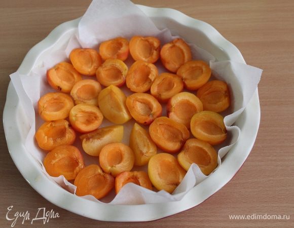 Форму 22 см застелить бумагой для выпечки, выложить дольки абрикос верх срезом.
