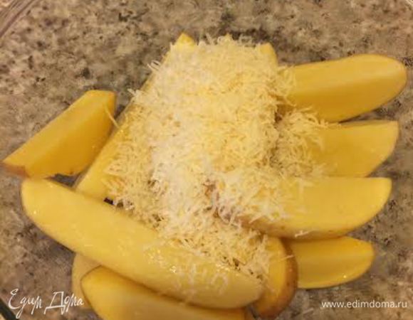 Духовку нагреть до 200°С. Картофель вымыть и обсушить бумажным полотенцем. Нарезать на дольки и смешать с оливковым маслом. Добавить натертый на мелкой терке пармезан и еще раз перемешать.