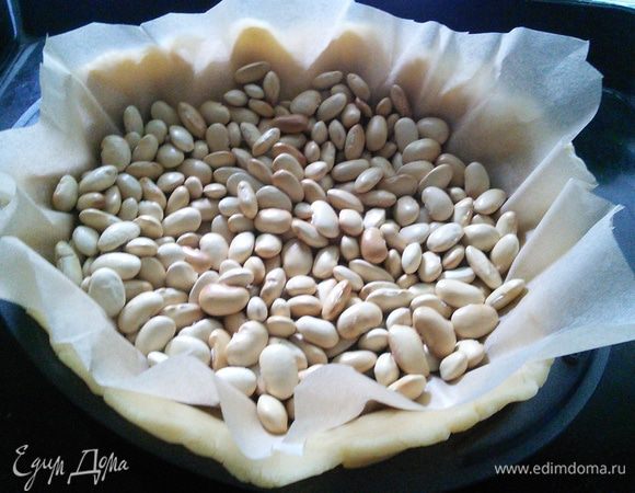 Разогреть духовку до 180°С. На тесто поместить пергамент с утяжелителем (любые бобовые) и поставить в холодильник, пока духовка разогреется. Выпекать корж в течение 20 мин. 