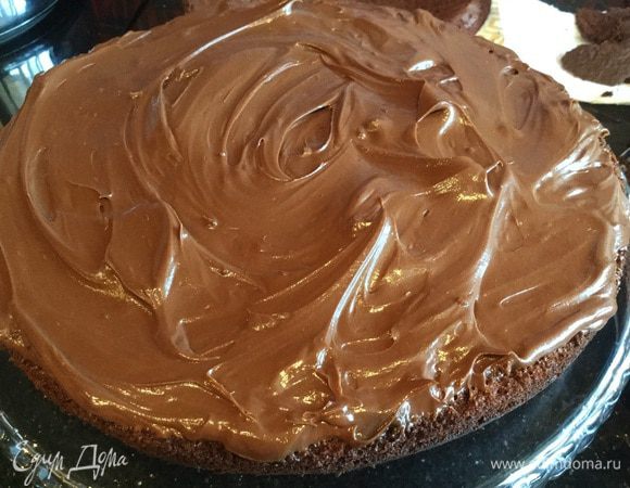 На сервировочное блюдо уложите первый бисквитный корж, смажьте 1/4 частью крема.