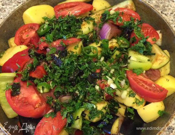 В сковороду налить оливковое масло, выложить мясо с овощами, сверху положить дольки помидора, 2 ст. л. зелени с чесноком и 1 ч. л. чабера.