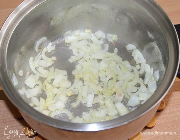 В кастрюлее с толстым дном обжарьте лук и чеснок до полупрозрачности.