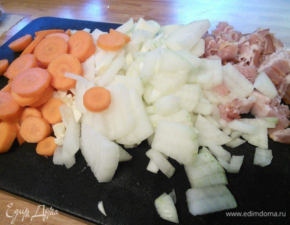 Так как жаркое в последствии будет запекаться в духовке, то удобнее готовить его в жаростойкой форме. Итак, в чугунке с толстым дном разогреть масло. Порубить лук, чеснок. Бекон мелко нарезать. Морковь — кружочками.