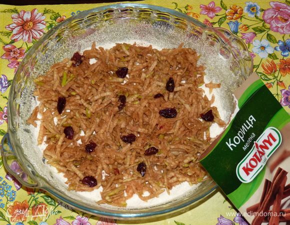 Форму смазать сливочным маслом, присыпать манкой. Затем насыпать слой в 1 см сухой смеси. Сверху слой тертых яблок. Присыпать корицей. Слить ликер с клюквы. Добавить немного клюквы к яблокам.