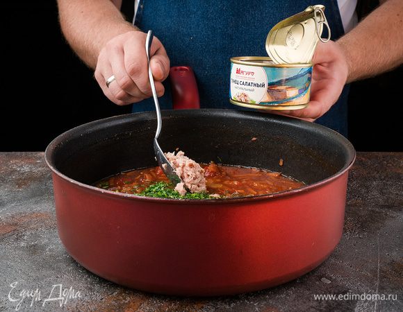 Через указанное время добавить в томатный соус кусочки тунца из банки и нарезанную зелень петрушки. Потушить все вместе еще минут 5 и снять с огня. 