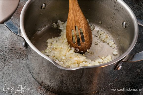 Очистите и мелко нарежьте лук и чеснок. В кастрюлю с толстым дном налейте растительное масло и обжарьте лук с чесноком.