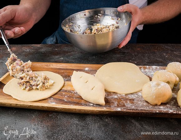 Тесто раскатать в лепешку, выложить начинку и сформировать пирожок. Пирожки выложить на противень, застеленный пекарской бумагой, швом вниз. Оставить на 15 минут. Разогревать духовку до 190°C. Через 15 минут смешать желток со сливками. Этой смесью смазать пирожки.