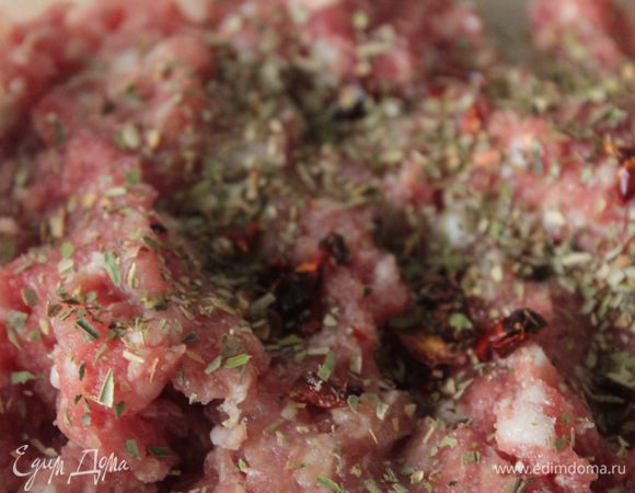 Смешать с фаршем половину мелко нарезанной луковицы, добавить орегано, специи, соль. Обжарить на оливковом масле небольшие тефтели и отложить в сторону.