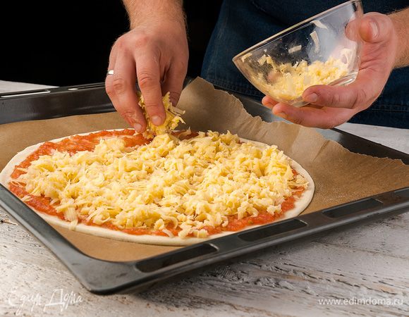 Потом посыпаем тертым сыром, сверху кладем нарезанную тонко колбасу, лук и перец. Отправляем пиццу в разогретую до 200°С духовку на 15 — 20 минут. 
