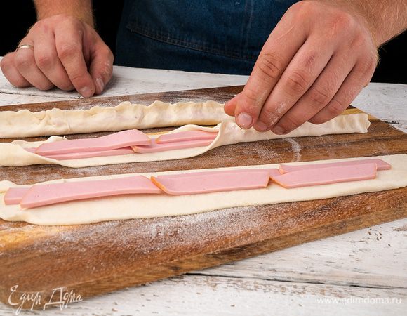 В середину квадратика из теста положить брусочек колбасы. 