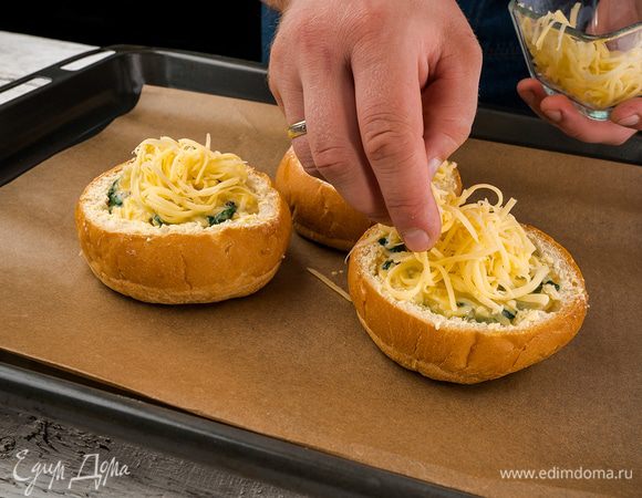 Яйца аккуратно поместить внутрь булочек. Посыпать сыром.