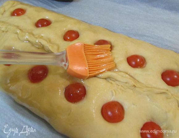 Наверху в пироге пальцем проделать дырочки. Черри разрезать на половинки. Выложить половинки в дырочки разрезом вниз. Верх пирога смазать растительным маслом.
