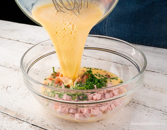 В отдельную посуду выложить нарезанные помидоры, ветчину, сыр и шнитт-лук, затем через сито влить взбитые яйца. 