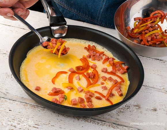 В сковороде растапливаем сливочное масло. Выливаем яичную смесь и готовим на среднем огне. Когда яйца схватятся, выкладываем нашу начинку из перца и ветчины, равномерно распределяя ее. Готовим еще несколько минут.