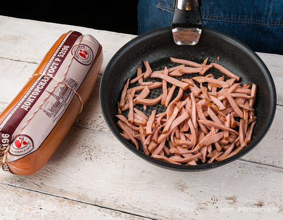 Колбасу нарезаем соломкой и обжариваем на сковороде пару минут. 