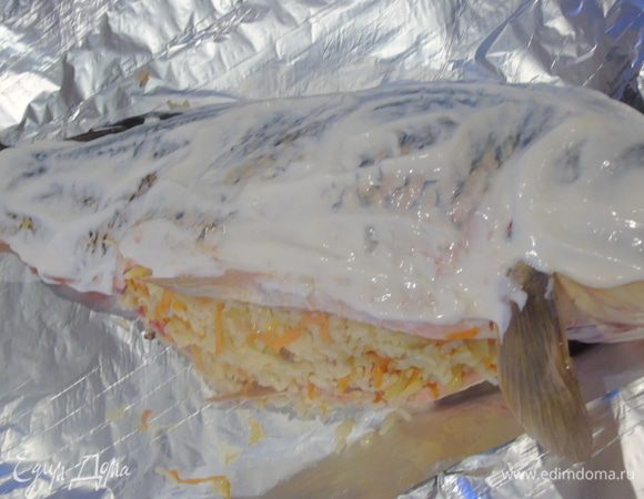 Смажьте карпа сметаной, заверните в фольгу и отправьте в разогретую до 180 — 200°С духовку на 1 час. Откройте фольгу и дайте рыбе подрумянится минут 10.  