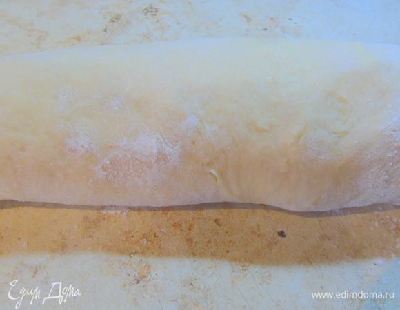 Через два часа тесто нужно обмять, руками растянуть в пласт и свернуть в рулет.