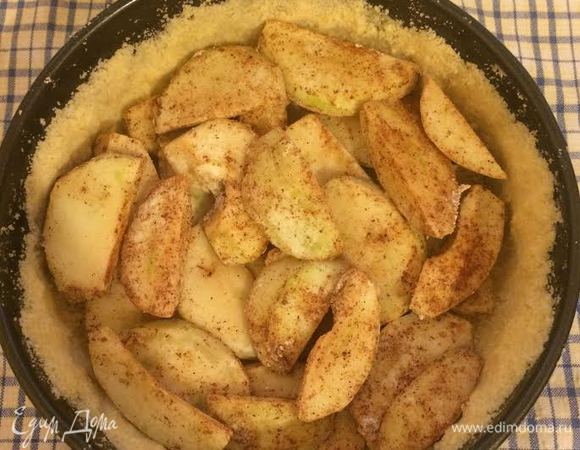 Форму диаметр 20 см, слегка смазать маслом. Тесто разделить на 3 части. Одну часть теста выложить на дно формы, вторую на бока, а третью оставить для обсыпки. Сверху на тесто выложить яблоки.