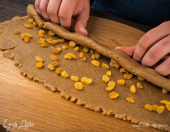 На тесто выложить изюм и сбрызнуть виноградным маслом. Скрутить тесто в рулет. 