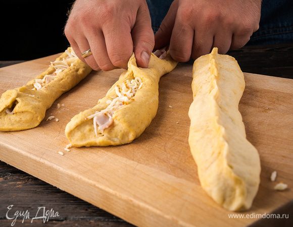 Раскатать каждый жгутик в длину примерно на 50 см и в ширину примерно на 10 см. Начинку равномерно распределить на три полоски. Защипнуть края. 

