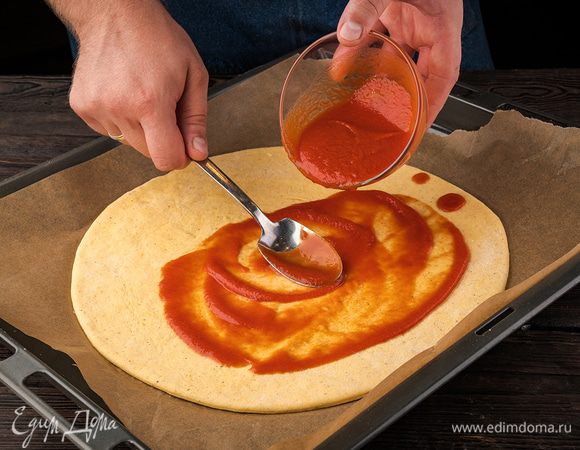 Тонко раскатать тесто и положить его в форму. Смазать всю поверхность теста томатным соусом.
