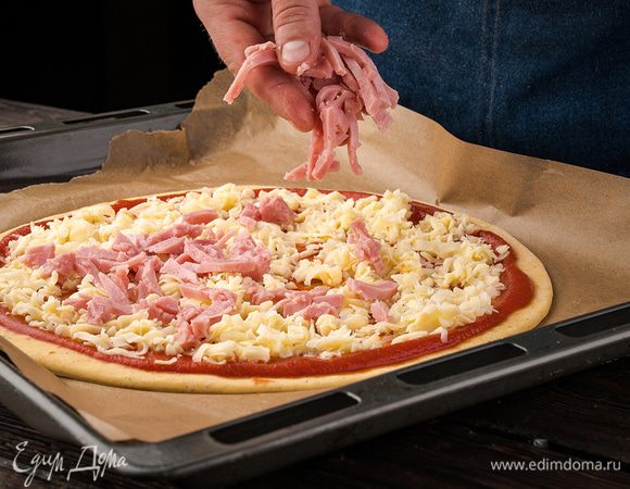 Сверху равномерно выложить нарезанную кубиками ветчину и обильно присыпать тертым сыром. Выпекать при температуре 165 °С 15–20 минут. 