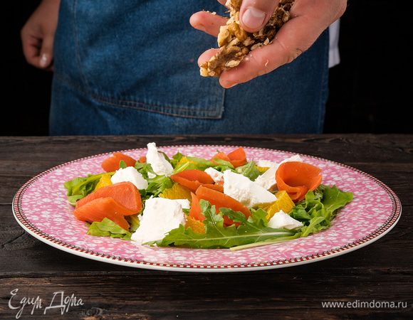 Апельсин, сыр и рыбу выложите сверху на руколу, еще раз сбрызните лимоном и добавьте немного масла. Посыпьте сверху салат грецкими орехами. 