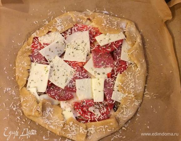 Перенести тесто на противень. Аккуратно завернуть края, смазать их молоком и присыпать тертым пармезаном.