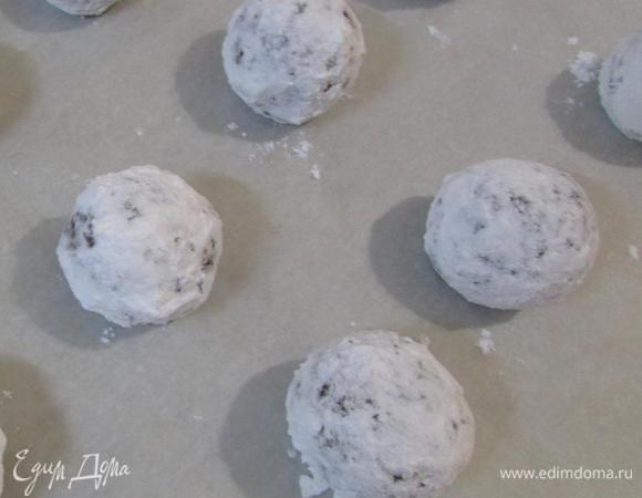 Каждый такой шарик нужно хорошенько обвалять в сахарной пудре. Затем выложить на противень, застеленный пекарской бумагой. Отправить в разогретую духовку (180°C). Выпекать 12 — 15 минут. Печенье извлечь из духовки. Остудить на решетке.