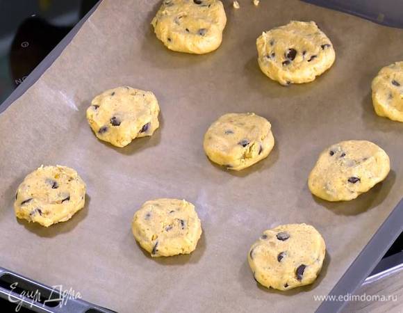 Сформировать из теста небольшие лепешки и выложить их на противень, выстеленный бумагой для выпечки.