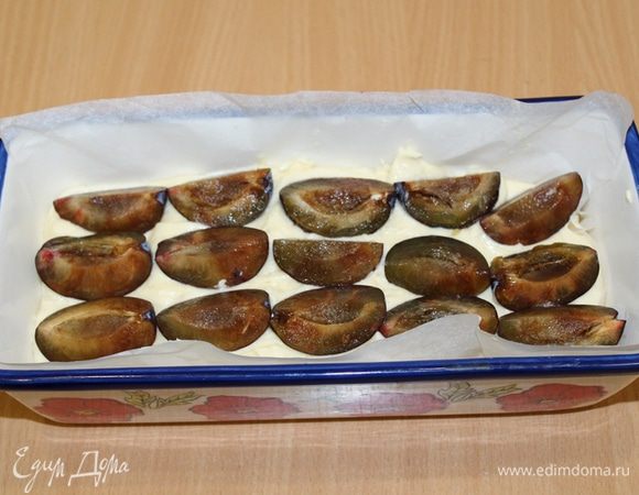 Выложить тесто в смазанную форму (или застелить бумагой), сверху выложить четвертинки слив.