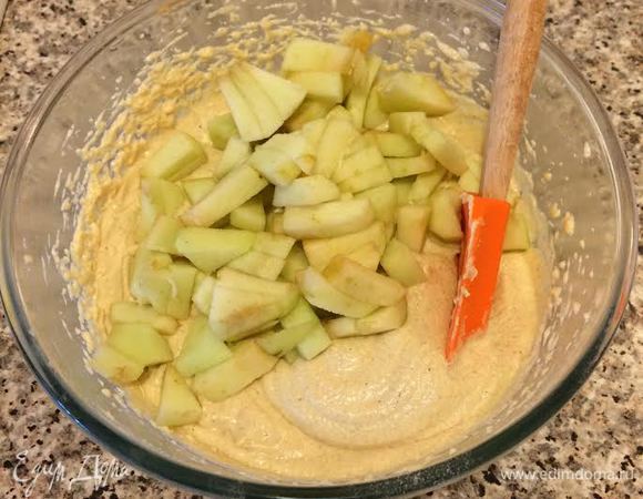 Добавить остальную муку, перемешать. Яблоки очистить и мелко нарезать, добавить в тесто и перемешать ложкой.