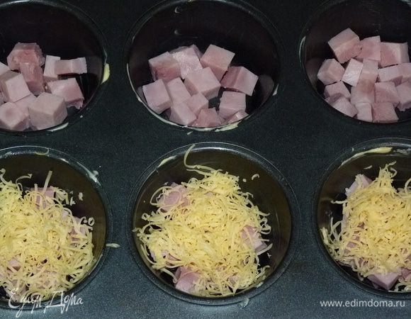 Нарезать ветчину кубиками и распределить по формам. Сыр натереть на терке. Равномерно распределить сверху ветчины. 