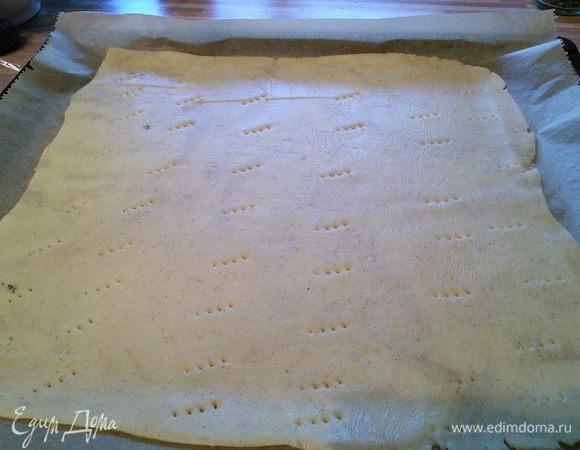 Песочное тесто раскатать на посыпанной мукой поверхности, выложить на смазанный маслом противень (можно раскатать прямо на пергаментной бумаге, выложить тесто с бумагой на противень), сделать проколы вилкой. Выпекать корж в заранее разогретой до 175°С  духовке 12 минут, вынуть из духовки, немного остудить, духовку не выключать.