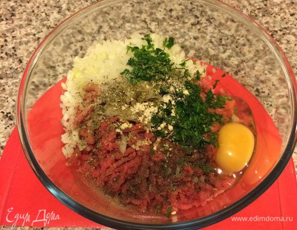 Лук и петрушку мелко нарезать. В фарш добавить лук, петрушку, хлебную крошку, яйцо, орегано, соль, перец, чесночный порошок и хорошо перемешать.